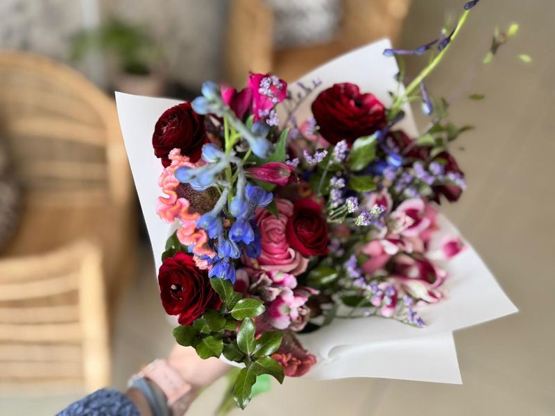 Rich mixed bouquet with dark ranunculus, blue delphinium and pink alstroemeria